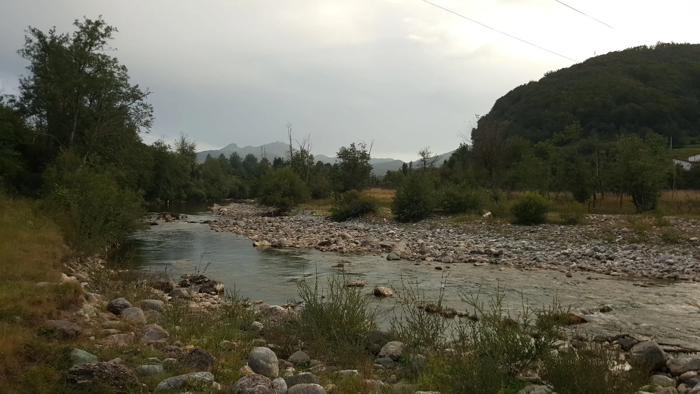 The Tara in evening light, a stony bank and a bend of clear water, wooded hills and peaks behind.
