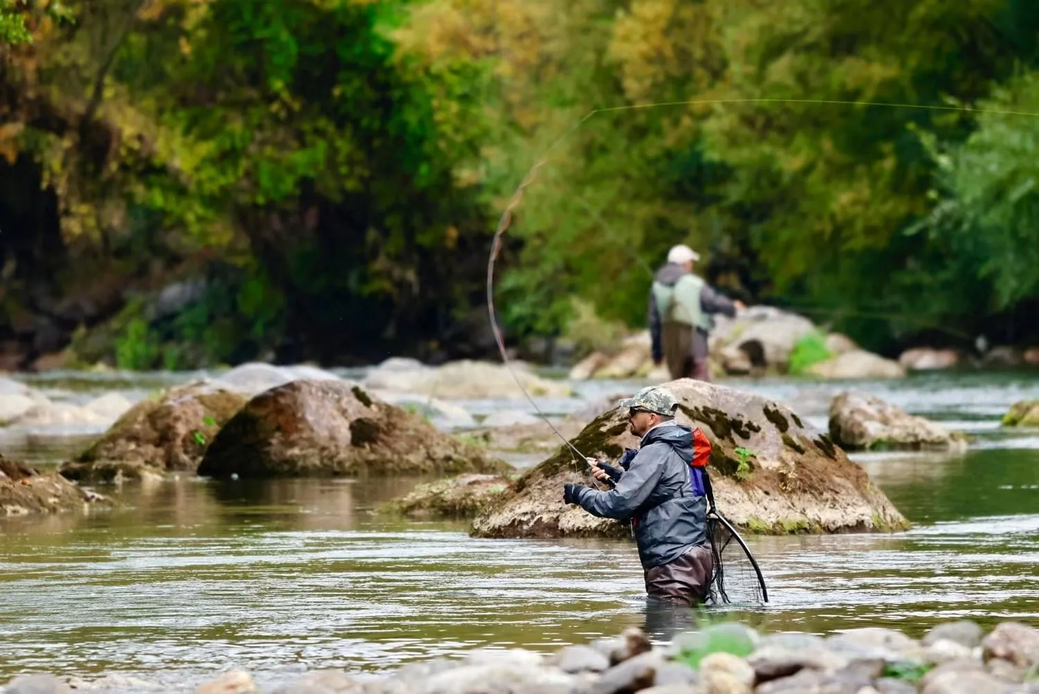 Aleksandar Gasevic fishing from the shore of a still mountain lake under autumn larches.